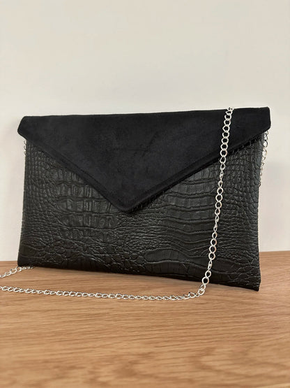 Le sac pochette Isa noir mat aspect reptile, avec chainette argentée.