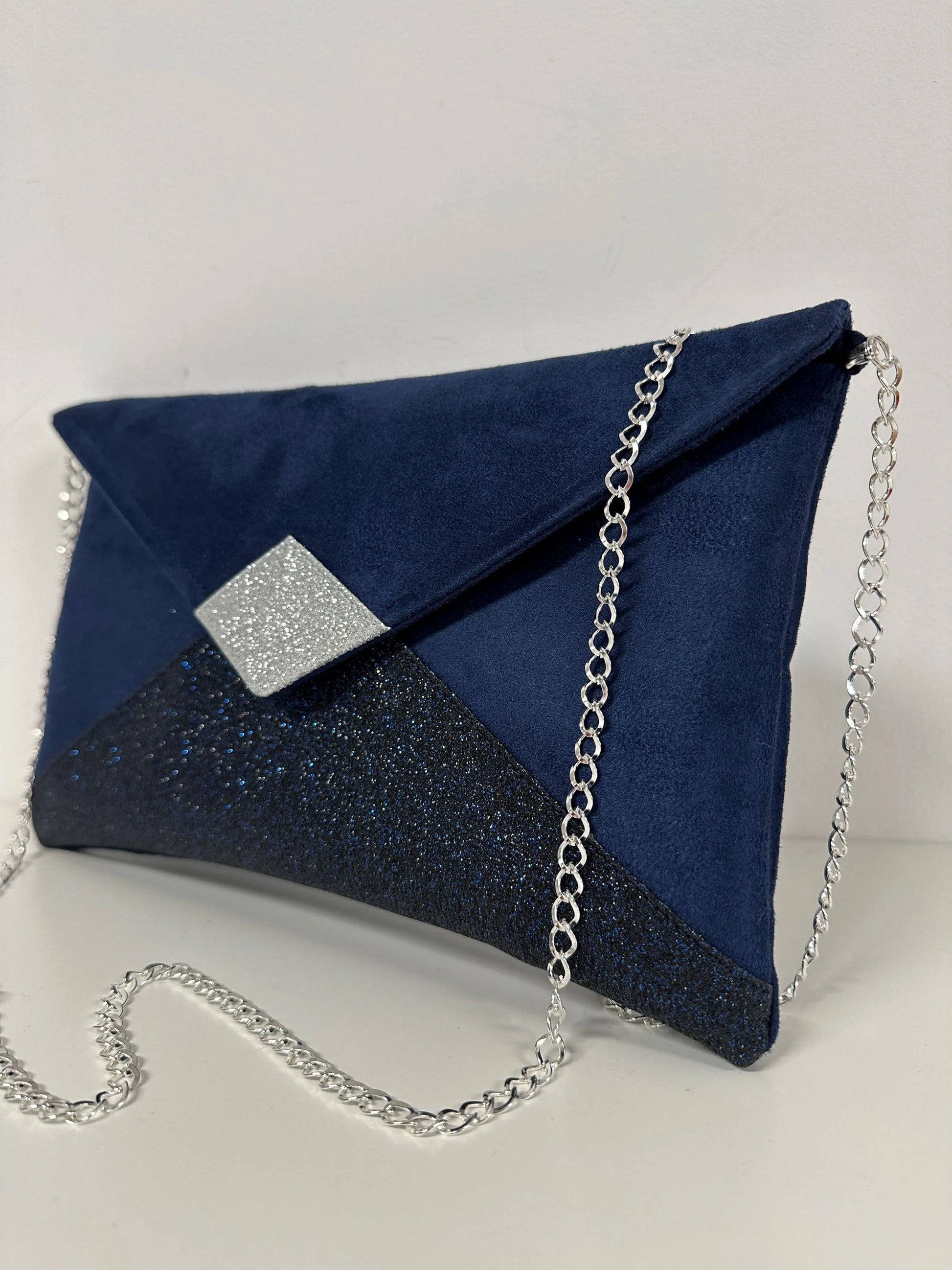Le sac pochette Isa à paillettes bleu marine et argentées, avec chainette amovible.
