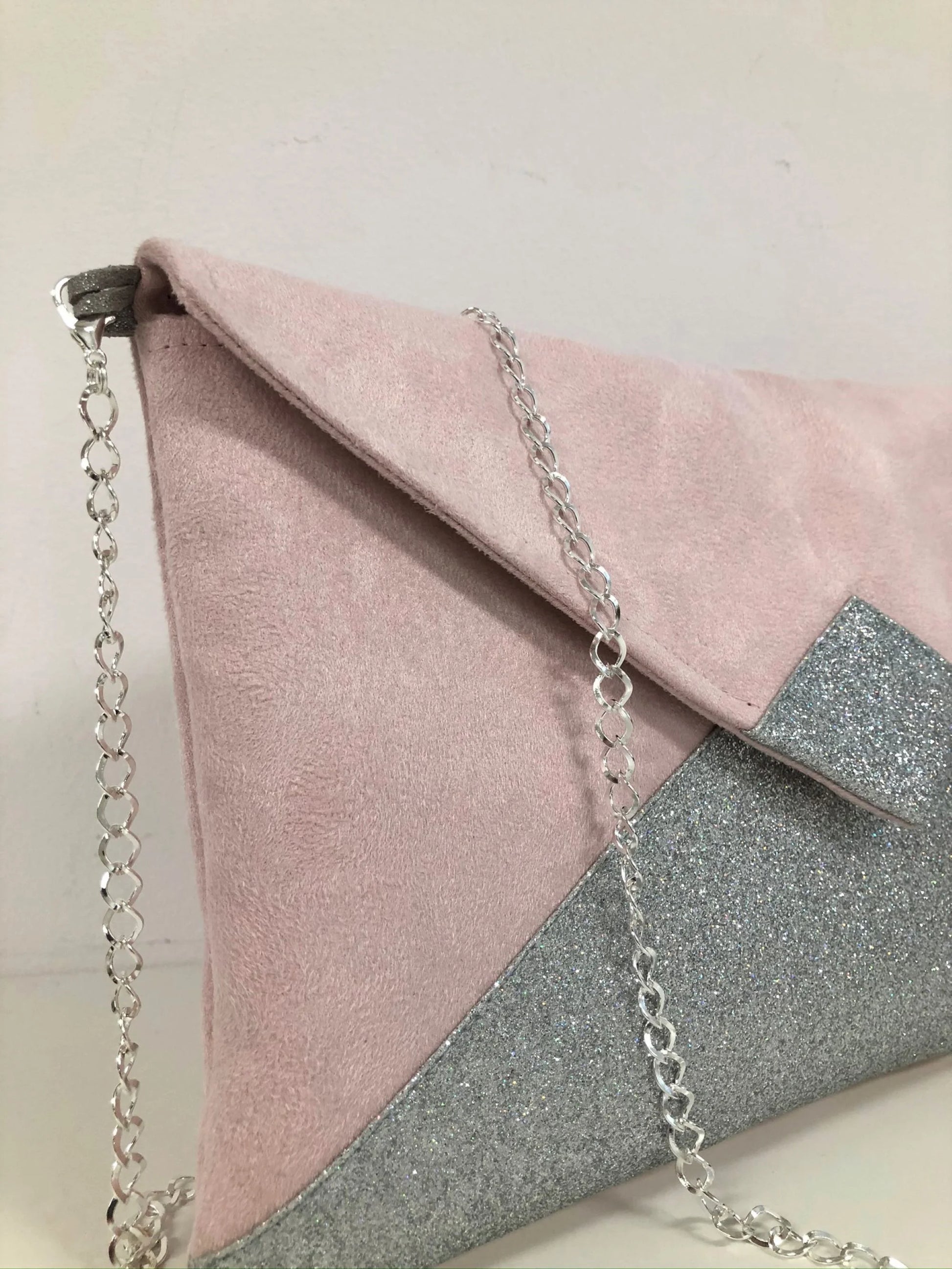 La chainette argentée amovible du sac pochette Isa rose pâle à paillettes argentées.