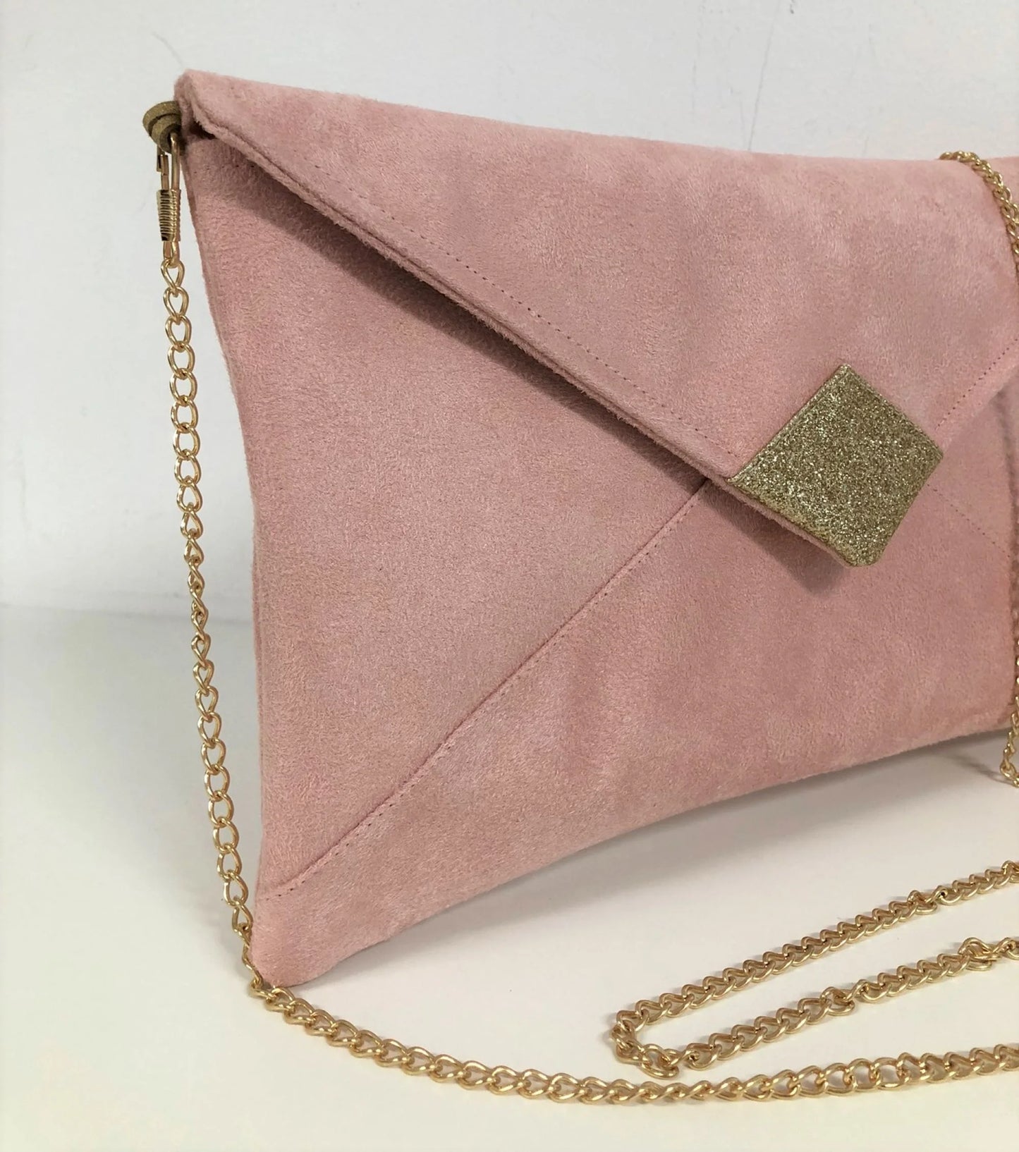 Le sac pochette Isa rose poudré à paillettes dorées, avec sa chainette dorée amovible.