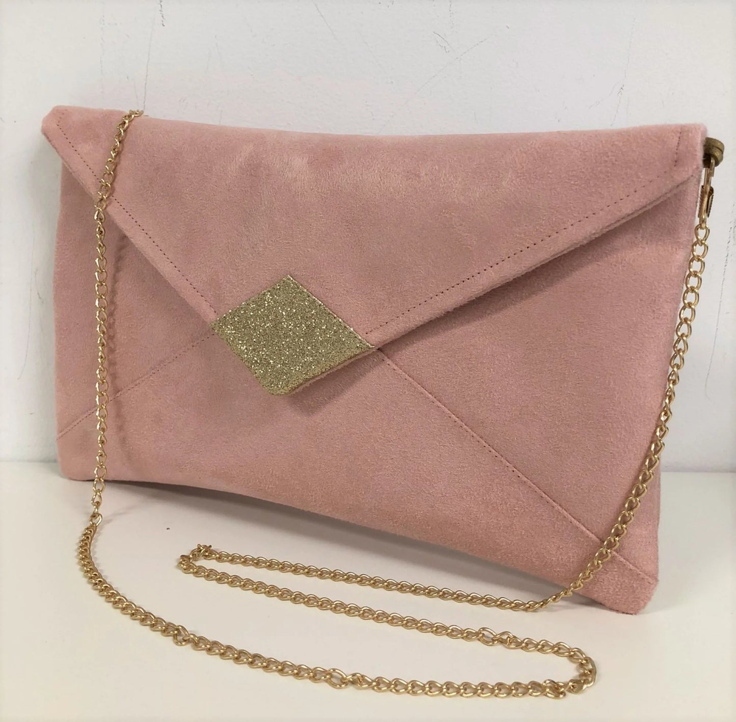 Le sac pochette Isa rose poudré à paillettes dorées, avec chainette amovible.