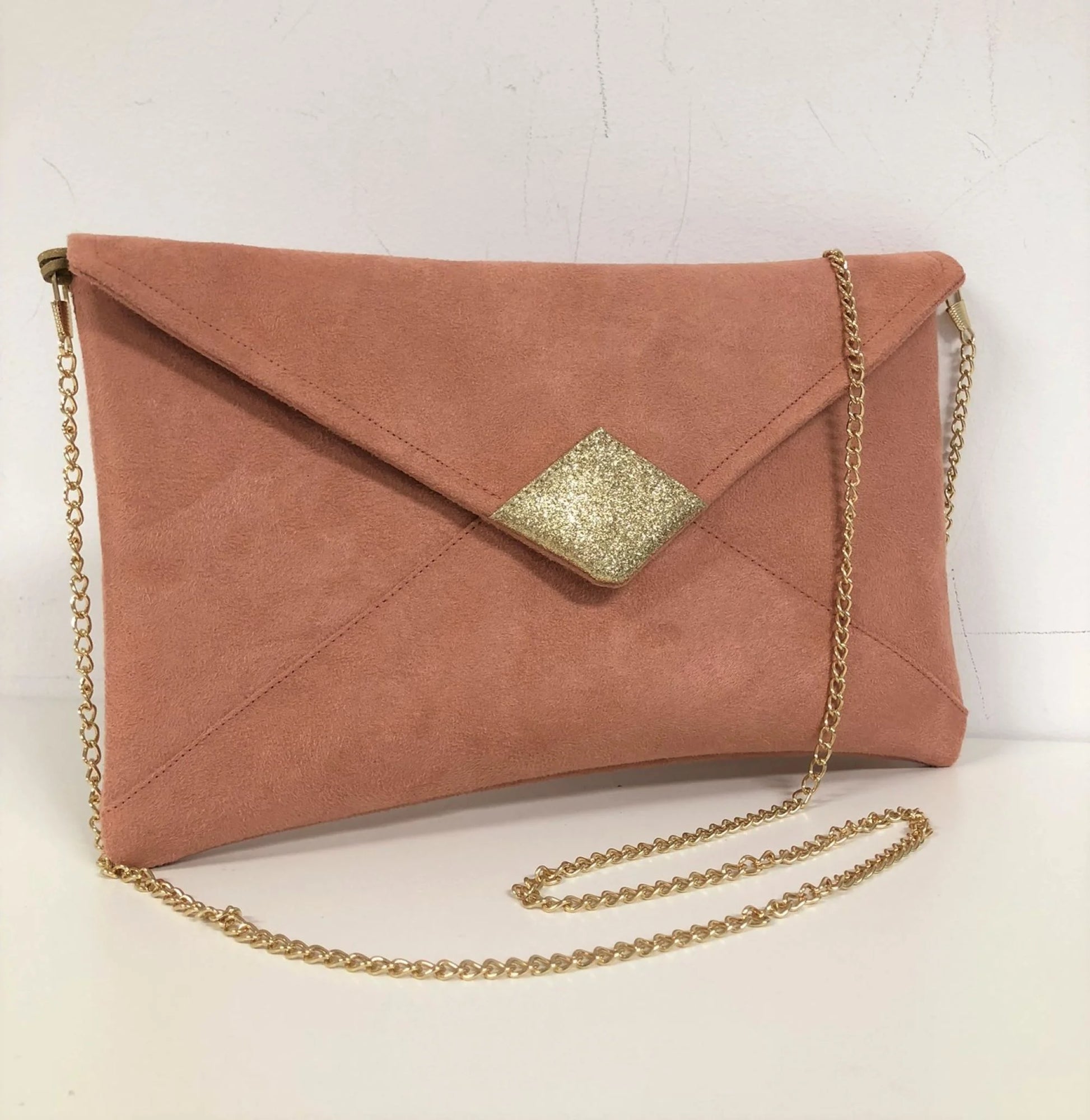 Le sac pochette Isa rose saumon à paillettes dorées, avec chainette amovible.