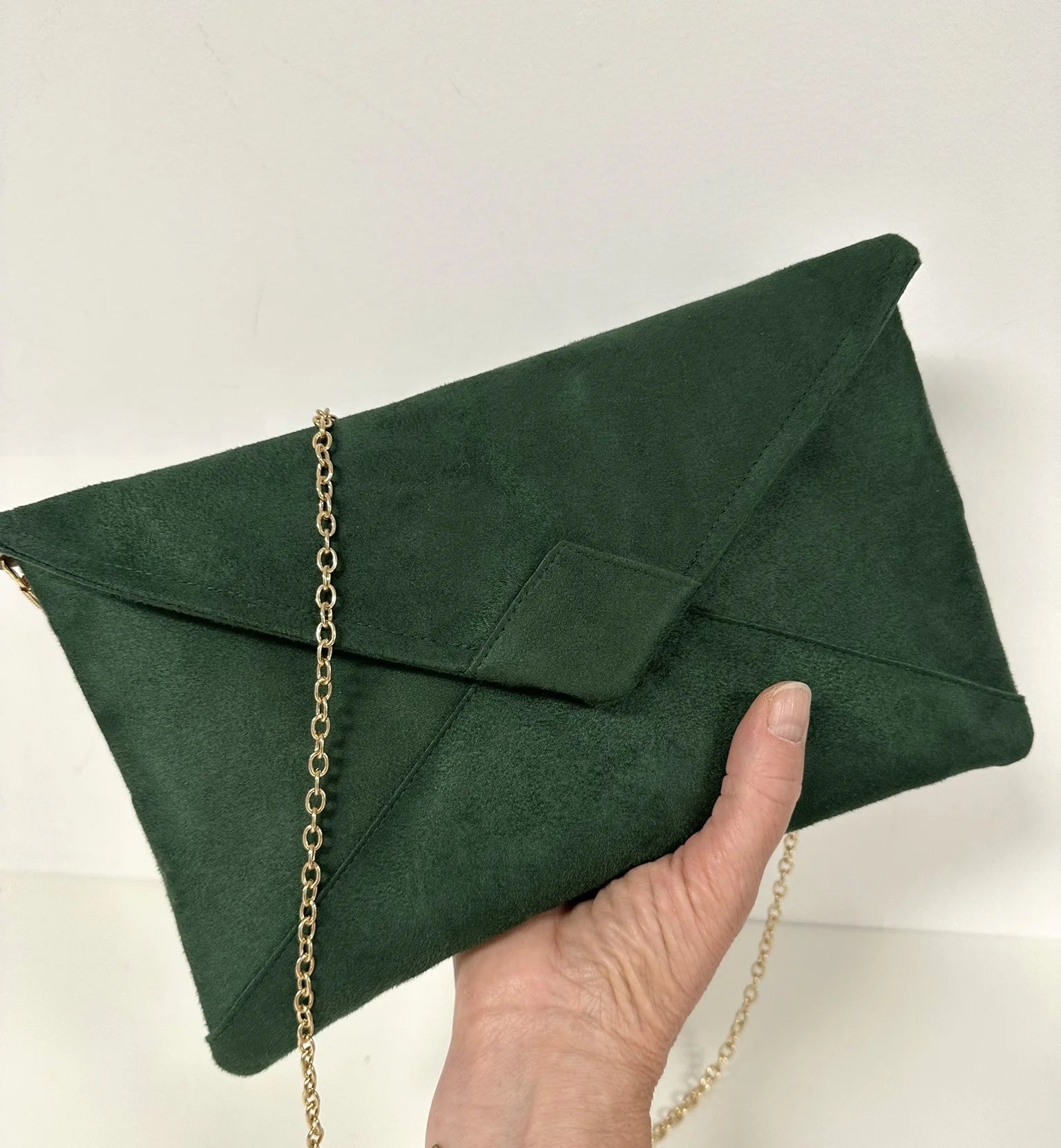 Le sac pochette Isa vert sapin tenu en main.