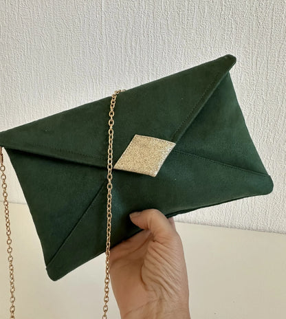 Le sac pochette Isa vert sapin et paillettes dorées tenu en main.