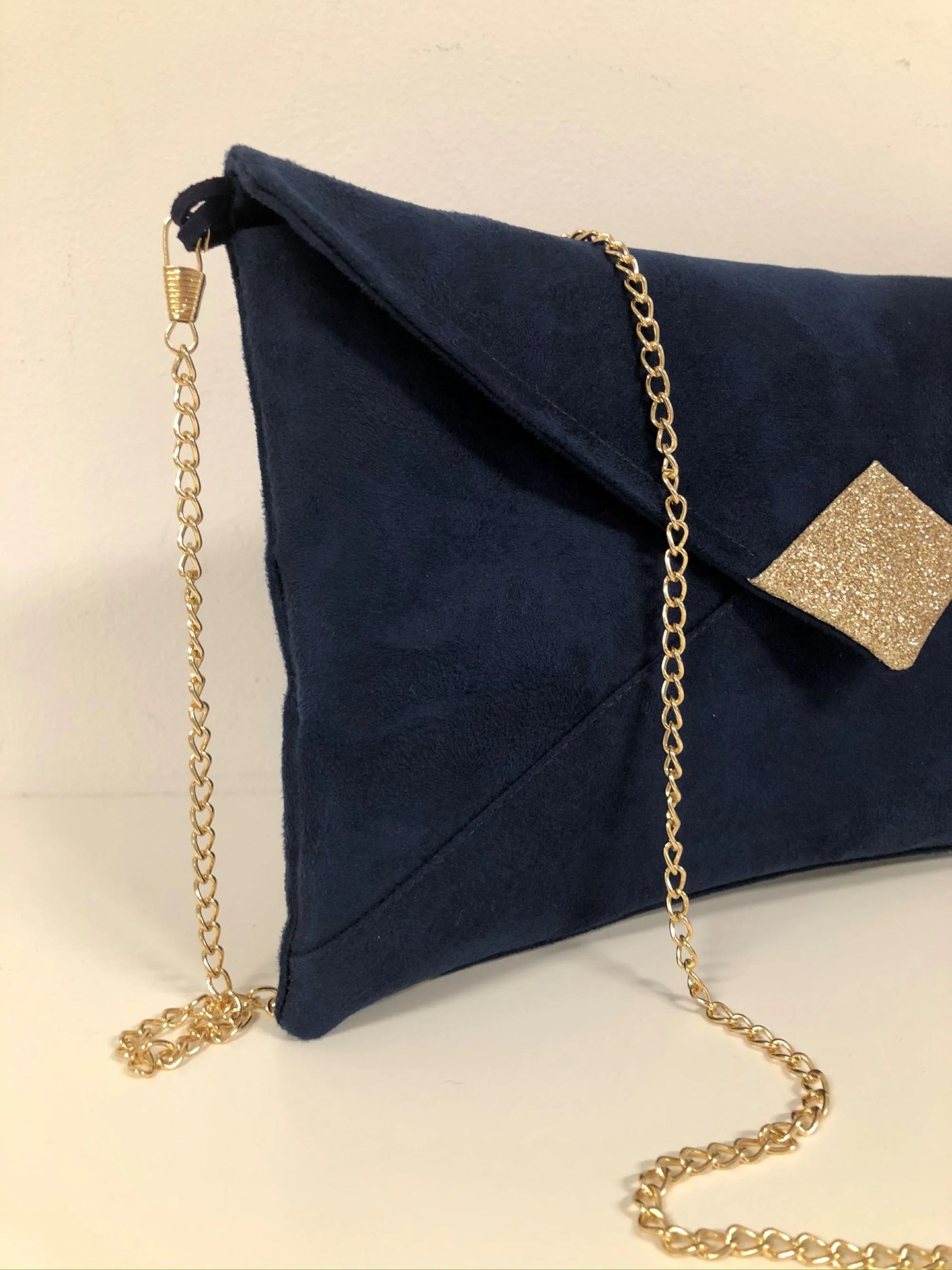 La chainette dorée amovible du sac pochette Isa bleu marine à paillettes dorées.