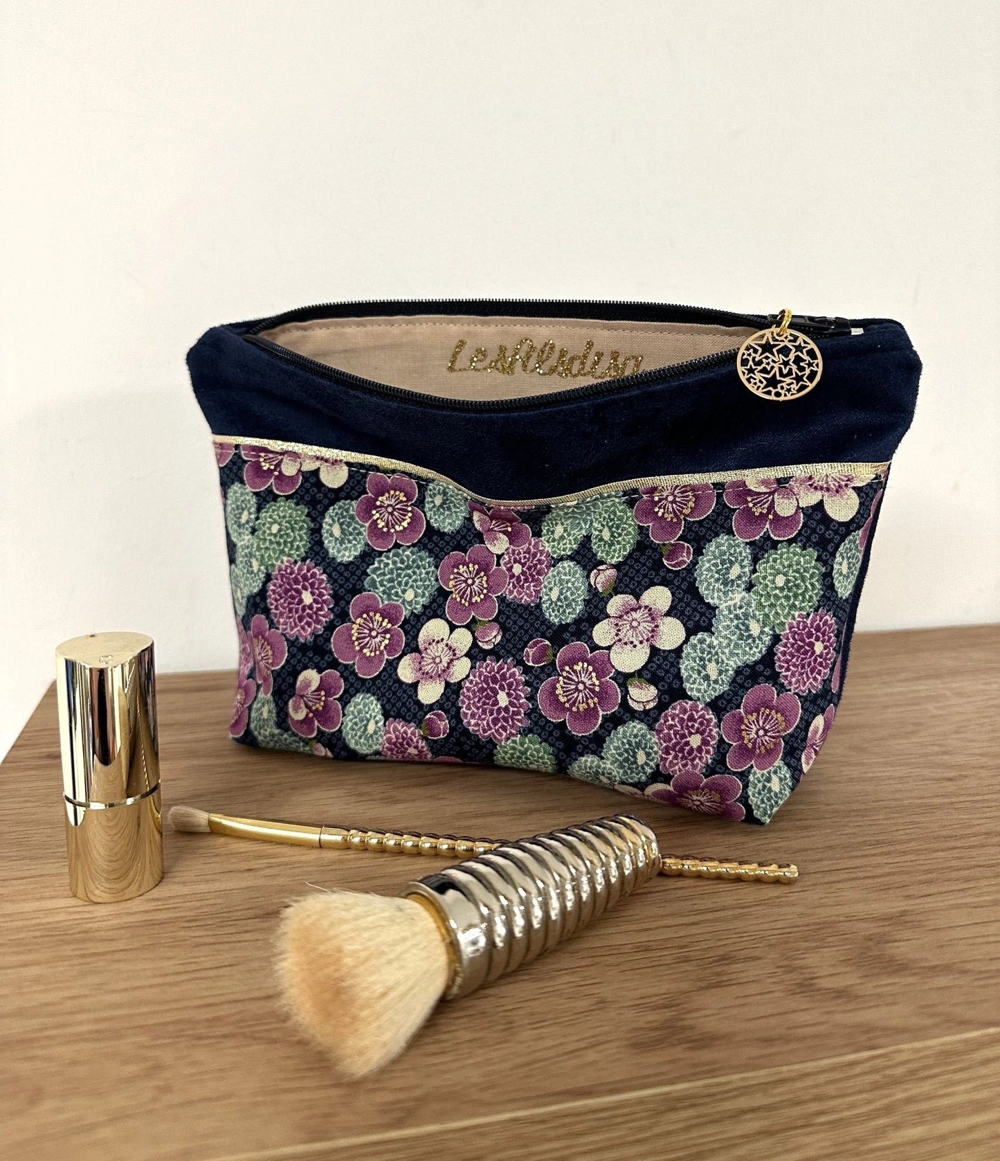 La trousse à maquillage bleu marine en tissu japonais à fleurs mauves, entrouverte.