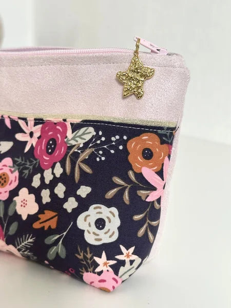 La breloque dorée de la trousse à maquillage fleurie rose et bleu.