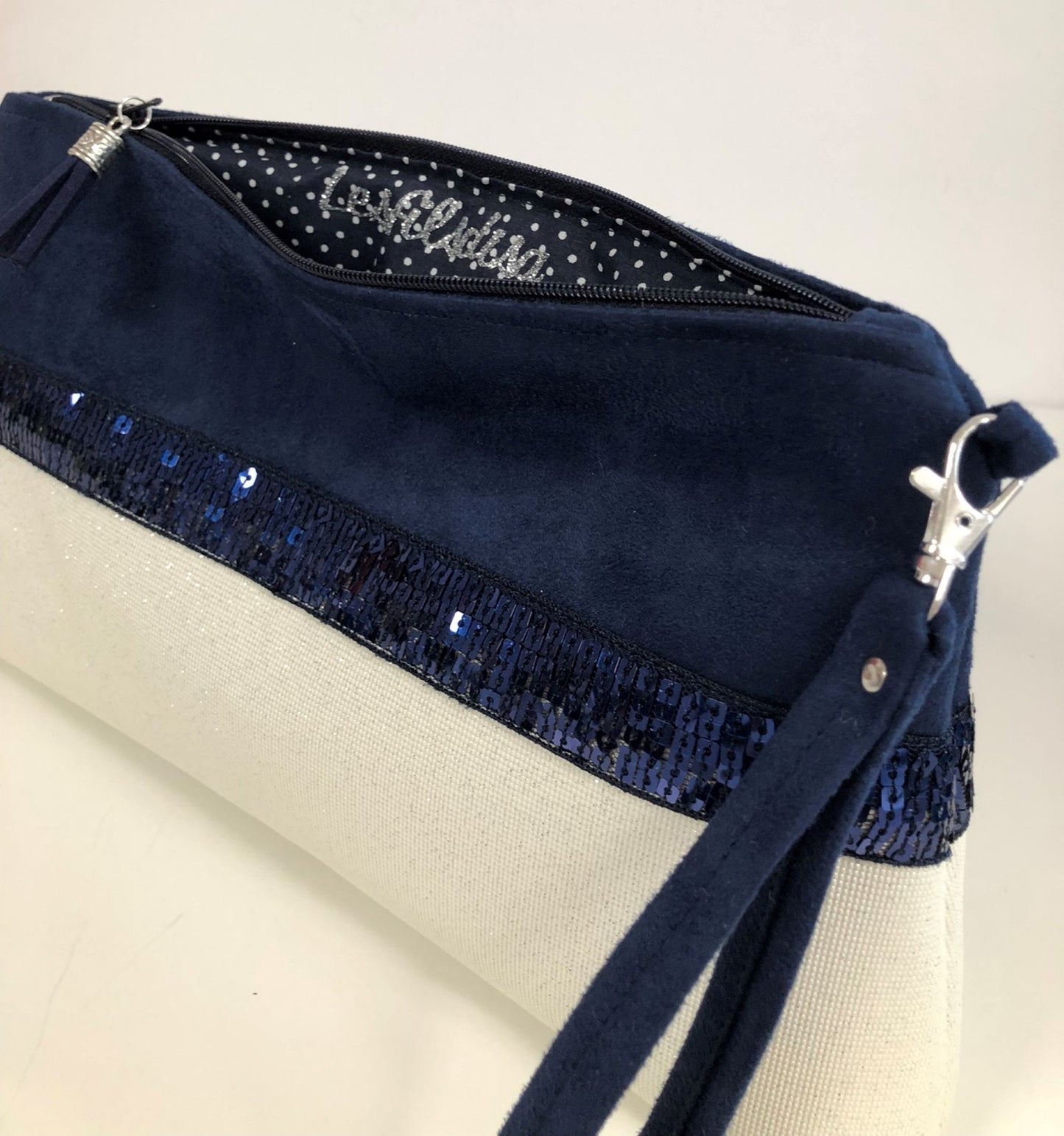 La pochette Isa zippée bleu marine et blanc à paillettes et dragonne amovible